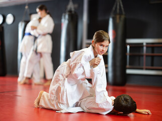 Engrossed sportsmen boy and girl in pair conduct training battle in oriental fighting judo...