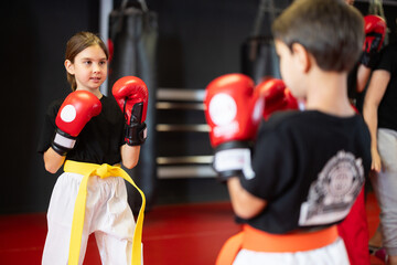 Boy and a girl in red boxing gloves work in sparring, they practice punches and practice stance....