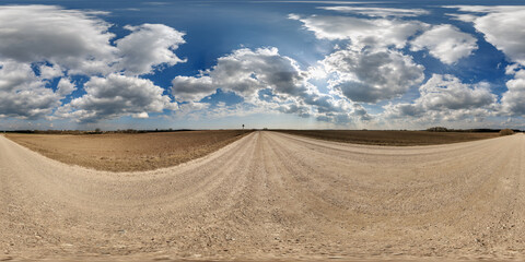 hdri 360 panorama view on gravel road among fields with clouds in sky in equirectangular full...