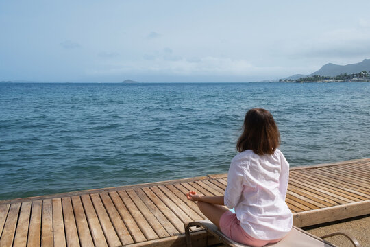 Relaxing by the sea while sitting peacefully on a wooden dock with a stunning ocean view