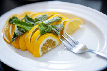 Delicious Fresh Lemon Slices Beautifully Arranged with Mint Garnish on a Bright White Plate