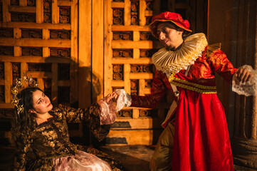 A flirting couple from the Spanish Colonial era, a man in a traditional Spanish red suit with a...