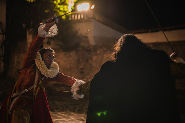 Spanish men in traditional colonial clothing dueling with swords called foils and daggers in a traditional 1600s town setting.