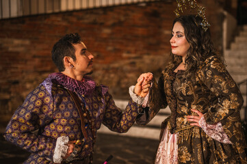 A flirting couple from the Spanish Colonial era, a man in a traditional Spanish suit dressed in purple and pink, and a girl with a princess-style tiara in a beautiful dress.