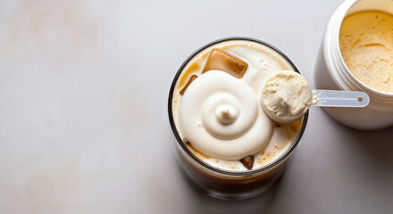 Top Down View of Iced Coffee with Cold Foam Topping, Protein Powder Scoop and Opened Jar in Corner of Frame Standing on Neutral Soft Colors Surface 