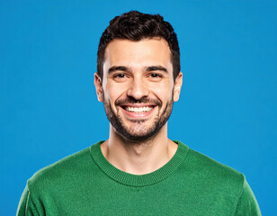 Fototapeta premium Vibrant portrait of smiling man wearing green sweater against blue background, radiating positivity and warmth