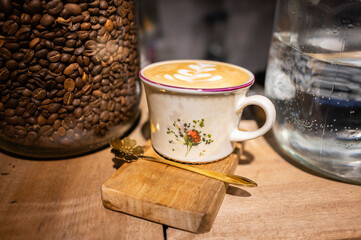Cappuccino with latte art served in floral cup with coffee beans and water
