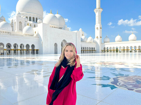 Woman in traditional Arab clothing, abaya, standing in Sheikh Zayed Grand Mosque in Abu Dhabi, UAE.