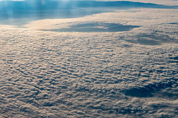 Aerial photograph showcasing an expansive, textured cloud cover. The clouds appear dense and...