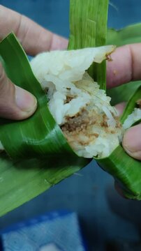 Close-up footage of Lemper, a traditional Indonesian snack made from glutinous rice filled with savory shredded chicken or beef. Typically wrapped in banana leaves