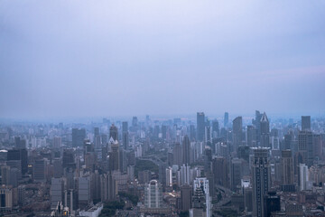 Aerial view of Shanghai city skyline under cloudy evening sky, showing dense high-rise buildings...