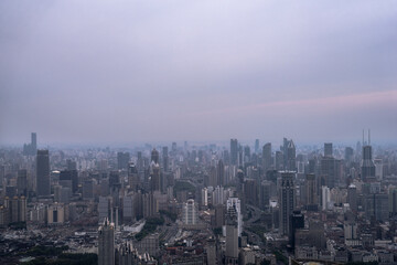 Aerial view of Shanghai city skyline under cloudy evening sky, showing dense high-rise buildings and sprawling urban layout.