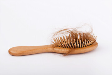 Wooden hairbrush with loose strands of hair on a clean surface
