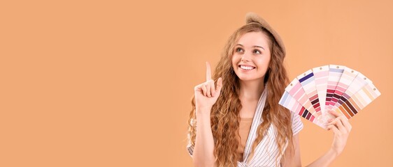Female interior designer with color palettes pointing at something on beige background with space...