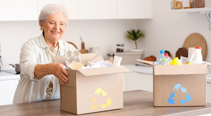 Senior woman with boxes of garbage in kitchen. Waste sorting concept
