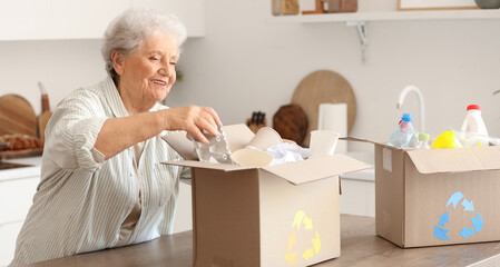 Senior woman with boxes of garbage in kitchen. Waste sorting concept