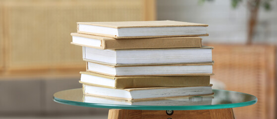 Stack of different books on glass table indoors