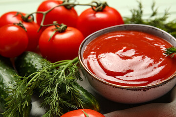 Bowl with tasty ketchup and fresh vegetables on table, closeup