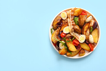Plate of tasty potato salad with eggs, tomatoes and bacon on light blue background, top view