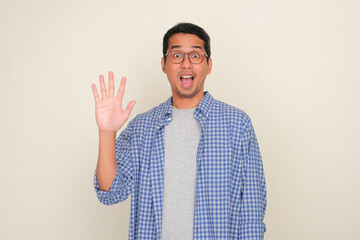 Adult Asian man showing wow face expression while giving five fingers sign