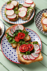 Plates with delicious radish bruschettas on green wooden table