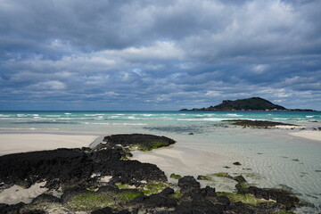 rock and sand beach and far island