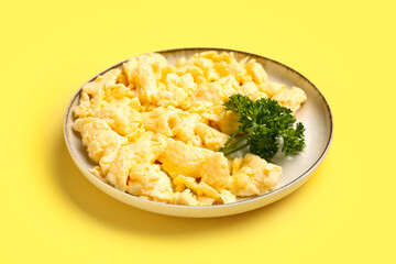 Plate of delicious scrambled eggs on yellow background