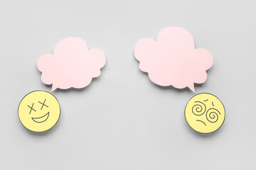Paper faces with blank speech bubbles on grey background