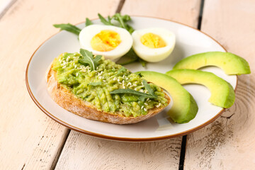 Plate of tasty bruschetta with avocado on light wooden background