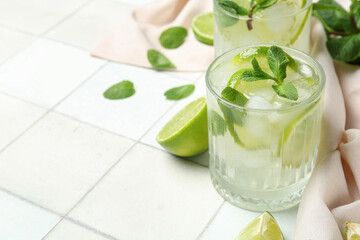 Glass of tasty mojito on white tile background