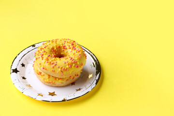 Paper disposable plate with donuts on yellow background