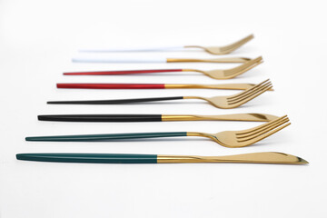 Golden forks and knives with colorful handles on white background