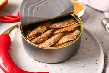 Plate of canned smoked sprats and chilli on grey background