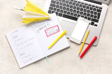 Mobile phone with laptop, umbrella and notebook on white background. Weather forecast concept