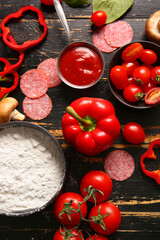 Different ingredients for preparing pizza on dark wooden background