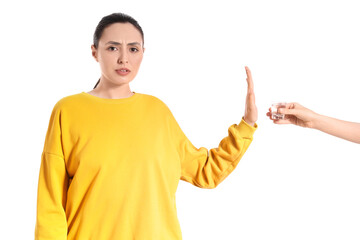 Young woman rejecting glass of vodka on white background