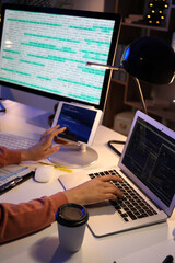 Female programmer working with devices in office at night, closeup