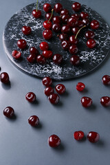 Board with sweet cherries on grey background