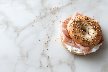 Toasted bagel topped with cream cheese and smoked ham, garnished with sesame seeds