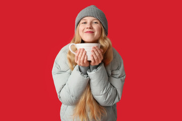 Beautiful young woman with big cup of tea on red background