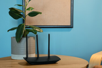 Modern wi-fi router with plant on table in living room at night