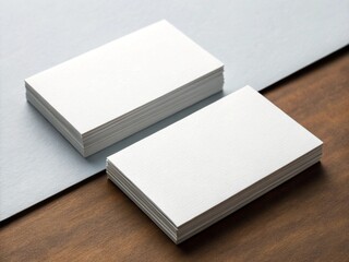Two stacks of blank white business cards are arranged on a textured gray and brown surface.
