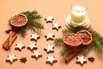 Star-shaped gingerbread cookies with cinnamon, dried orange, fir branches and burning candle on brown background