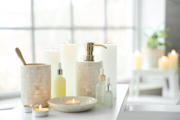 Toothbrushes, candles and different cosmetics on white bathtub tray