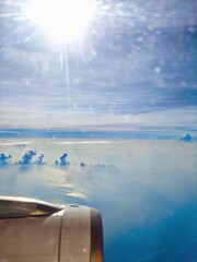 View from Airplane Window above Clouds with Bright Sunlight