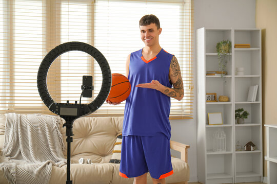Sporty happy basketball player with ball recording video at home - Powered by Adobe