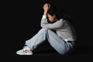 Young African-American woman having panic attack on black background