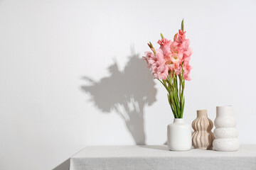 Vase with bouquet of beautiful gladiolus flowers on table against white background