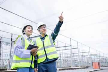 Engineer and technician working at high voltage power substation performing inspection and check of electrical infrastructure to ensure safety and reliability of system