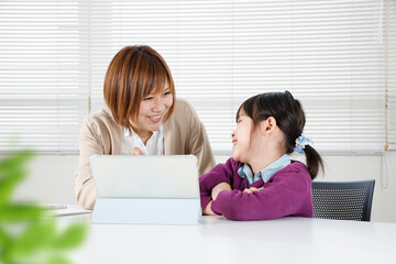 褒められてうれしい子供とタブレットを使って勉強を教える女性